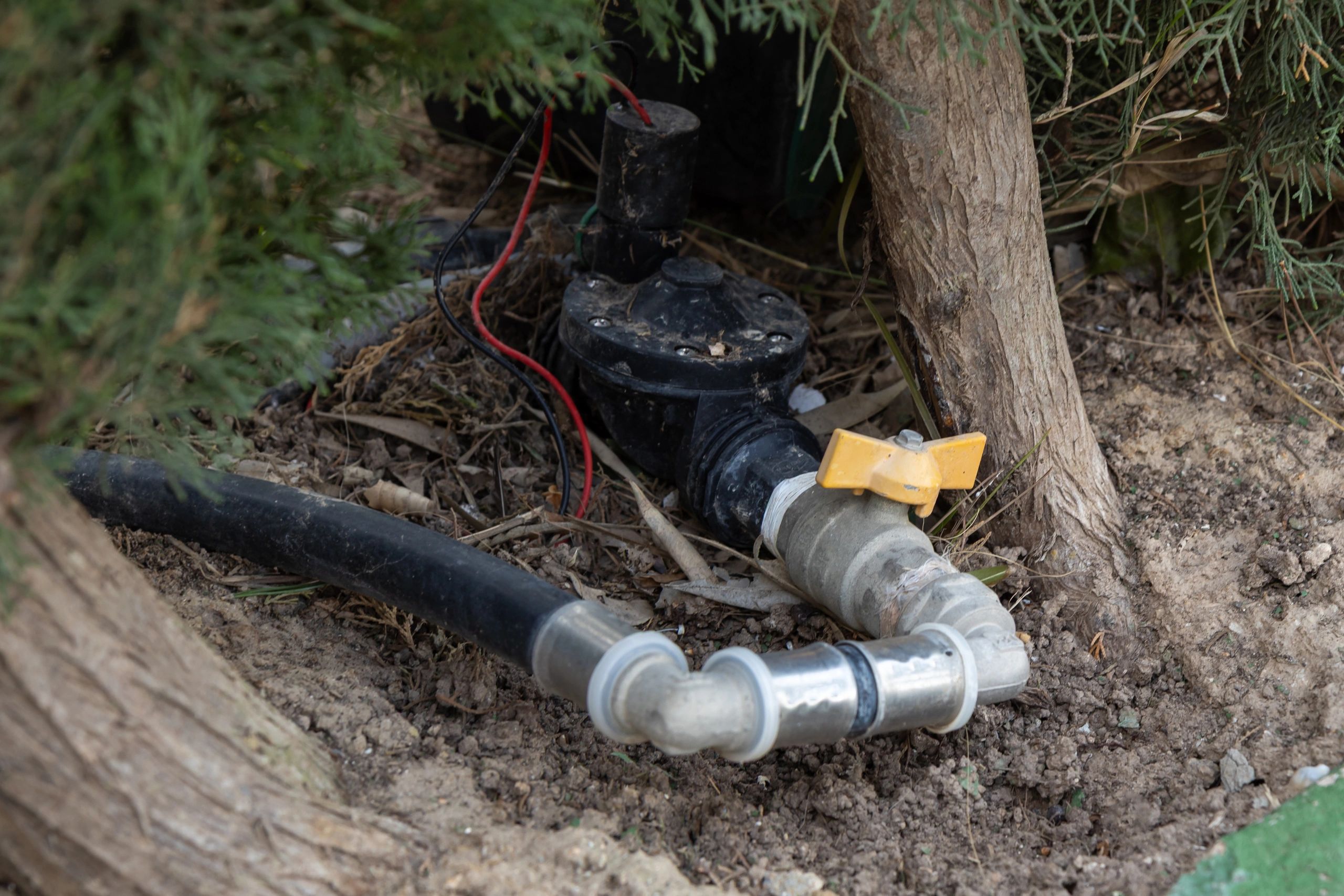 Close-up of irrigation valve and hoses installed in soil
